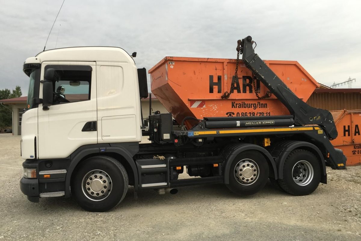 Absetzkipper von Hartl mit oranger Mulde, dahinter weitere Container