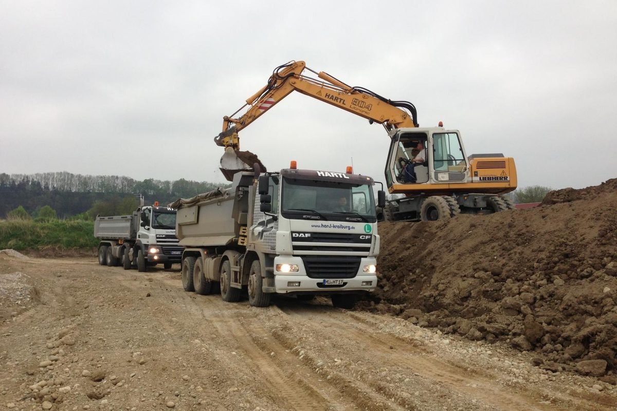 Kettenbagger belädt zwei Kipper von Hartl auf einer Baustelle